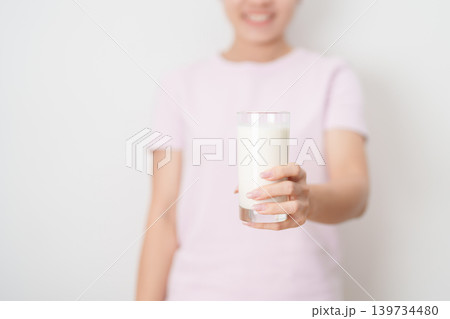 Healthy woman holding glass of fresh milk at home, female drinking milk for calcium and strong bones, high protein, dairy product for healthy lifestyle, wellness and daily routine concept 139734480