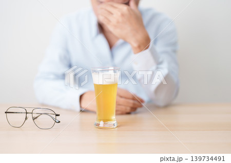 Stressed man drinking beer alone with problem. Exhausted drunk man looking stressed and sleepy. Alcohol addiction, Alcoholism, emotional distress and mental health concept 139734491