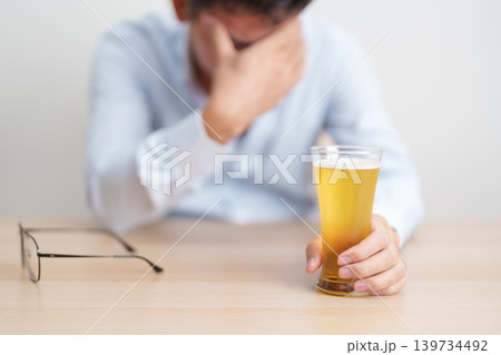 Stressed man drinking beer alone with problem. Exhausted drunk man looking stressed and sleepy. Alcohol addiction, Alcoholism, emotional distress and mental health concept Stressed man drinking beer alone with problem. Exhausted drunk man looking stressed and sleepy. Alcohol addiction, Alcoholism, emotional distress and mental health concept 139734492