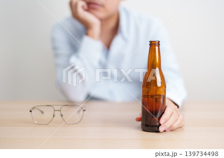 Stressed man drinking beer alone with problem. Exhausted drunk man looking stressed and sleepy. Alcohol addiction, Alcoholism, emotional distress and mental health concept Stressed man drinking beer alone with problem. Exhausted drunk man looking stressed and sleepy. Alcohol addiction, Alcoholism, emotional distress and mental health concept 139734498