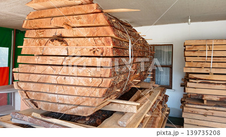 Large wooden log stacked in workshop with tools and equipment visible Large wooden log stacked in workshop with tools and equipment visible 139735208