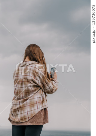 Woman smartphone sky capturing the overcast horizon while wearing a plaid shirt jacket on a cloudy day Woman smartphone sky capturing the overcast horizon while wearing a plaid shirt jacket on a cloudy day 139736078