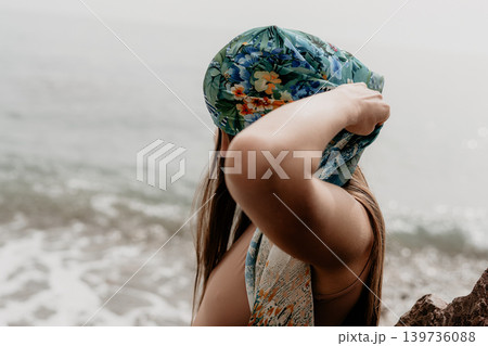 Woman headscarf beach young woman wearing floral silk scarf on a sunny shore with blurred ocean waves and copy space 139736088