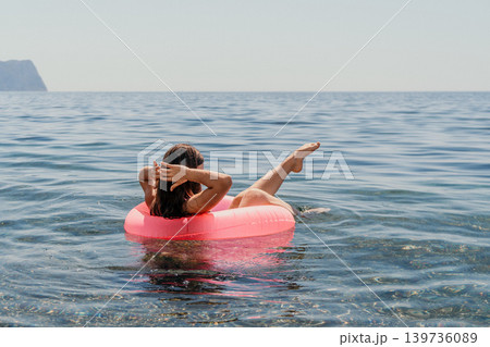 Woman floating tube young lady relaxing on a pink inner tube in the clear blue sea with horizon and copy space 139736089