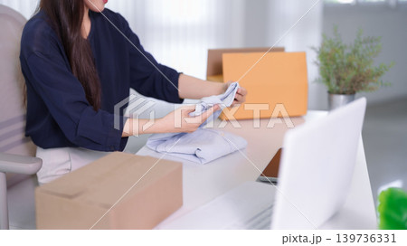 Asian women entrepreneur small business owner prepare clothing product folding shirt package parcel box online selling ecommerce live streaming merchant Asian women entrepreneur small business owner prepare clothing product folding shirt package parcel box online selling ecommerce live streaming merchant 139736331