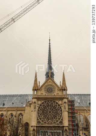 Notre dame cathedral spire in Paris, France, undergoing reconstruction with scaffolding and cranes against a cloudy sky 139737293