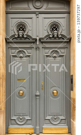 Ornate grey door of a classical parisian building with carved lions, fancy wrought iron grilles, and shiny golden hardware Ornate grey door of a classical parisian building with carved lions, fancy wrought iron grilles, and shiny golden hardware 139737297