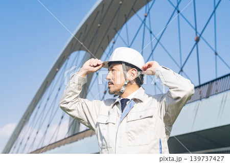 橋の前で遠くを眺める男性作業員 139737427