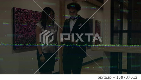 Reviewing tablet, man in suit and woman in satin blouse skirt studying data overlay in gallery Reviewing tablet, man in suit and woman in satin blouse skirt studying data overlay in gallery 139737612
