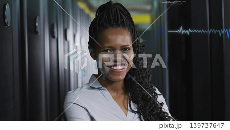 Standing adult woman wearing collared blouse smiling in data center aisle, with racks and waveform Standing adult woman wearing collared blouse smiling in data center aisle, with racks and waveform 139737647