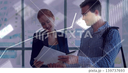 Reviewing two colleagues examining papers near glass windows, navy blazer and checked shirt, chart 139737693