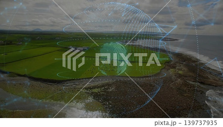 Hovering mesh globe projecting orbital rings over coastal fields and rocky shore, showing farms Hovering mesh globe projecting orbital rings over coastal fields and rocky shore, showing farms 139737935