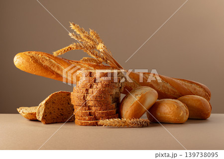 Sliced bread, baguette, and French buns with wheat ears on a beige background. 139738095