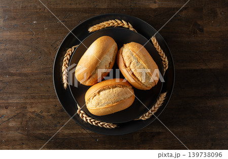 French buns and wheat ears on a black plate. French buns and wheat ears on a black plate. 139738096