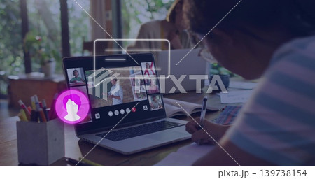 Writing schoolchild in striped shirt using notebook in online class at wooden table, laptop Writing schoolchild in striped shirt using notebook in online class at wooden table, laptop 139738154