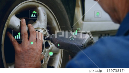 Stabilizing wheel hub and operating impact wrench in workshop, wearing blue shirt with AR overlays 139738174