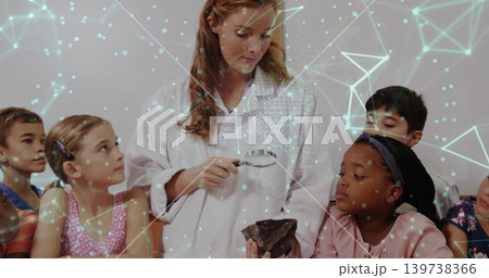 Examining teacher in white lab-coat holding lens at school inspecting rock with AR network overlay 139738366