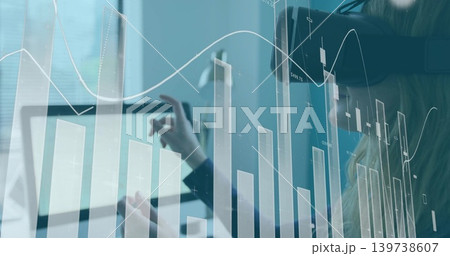 Analyzing blazer-wearing analyst touching tablet at desk, with financial chart overlay and headset Analyzing blazer-wearing analyst touching tablet at desk, with financial chart overlay and headset 139738607