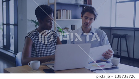 Discussing woman checked dress man light blue shirt reviewing laptop and color charts office table Discussing woman checked dress man light blue shirt reviewing laptop and color charts office table 139738726