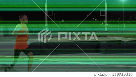 Striding runner orange top dark shorts on night track with mat and green streaks, copy space 139739316