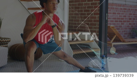 Performing man in red sleeveless top, blue shorts lunging in home with mat, water bottle 139739339