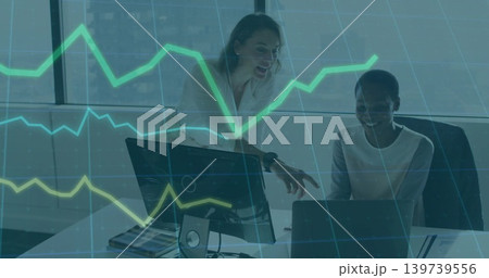 Pointing two women working in office in blazers, using laptop and screen with green-yellow chart Pointing two women working in office in blazers, using laptop and screen with green-yellow chart 139739556