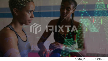 Balancing blue ball, two women in sports tops training in gym with candlestick overlays, pink mat Balancing blue ball, two women in sports tops training in gym with candlestick overlays, pink mat 139739669