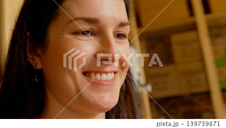 Smiling woman in dark top leaning in storage, showing hoops, wooden shelving, boxes, copy space Smiling woman in dark top leaning in storage, showing hoops, wooden shelving, boxes, copy space 139739871
