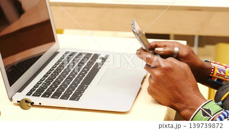 Holding phone, mature hands showing beaded bracelets and fabric cuff at desk, laptop emoji sticker Holding phone, mature hands showing beaded bracelets and fabric cuff at desk, laptop emoji sticker 139739872
