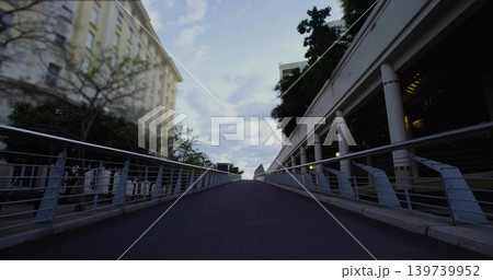 Ascending paved pedestrian ramp leading toward distant horizon at city plaza, with metal railings 139739952