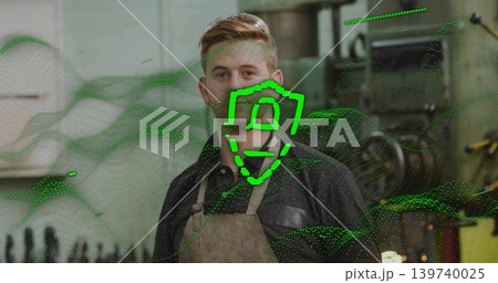 Standing machinist wearing leather apron, dark shirt in shop with lathe, shelves, green overlay Standing machinist wearing leather apron, dark shirt in shop with lathe, shelves, green overlay 139740025