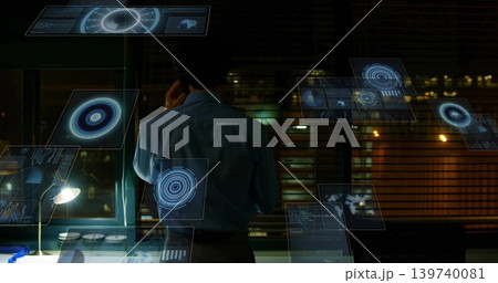 Talking man in blue shirt, dark pants using smartphone at dim office, monitoring holographic UI 139740081
