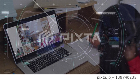 Displaying laptop showing remote classroom on home desk, with child writing using green pencil 139740235