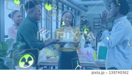 Holding birthday cake, woman in business attire wearing tiara smiling with team in office, balloons Holding birthday cake, woman in business attire wearing tiara smiling with team in office, balloons 139740362