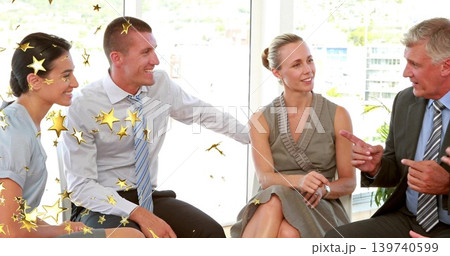Discussing team of four exchanging ideas by glass office window, in suits with gold stars Discussing team of four exchanging ideas by glass office window, in suits with gold stars 139740599