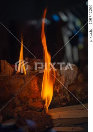 Tall fire extending from wooden log scene. Vertical flame emerging from aged wood with sparks and texture Tall fire extending from wooden log scene. Vertical flame emerging from aged wood with sparks and texture 139742266