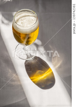 Glass of Cold Beer on a Sunny Restaurant Terrace Table with Long Shadows in Italy 139742381