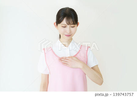 白背景のピンクのエプロンをつけた若い日本人女性介護士のポートレート 白背景のピンクのエプロンをつけた若い日本人女性介護士のポートレート 139743757