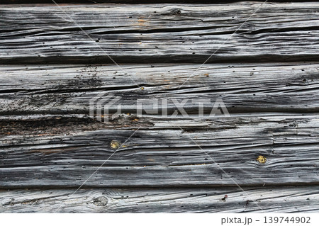 Planks of wood form a wall with visible lines and marks. The wood displays signs of age and weathering from being exposed to the elements 139744902