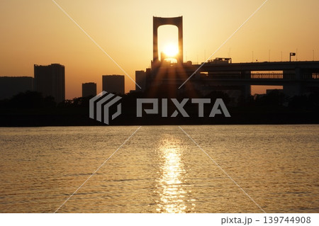 レインボーブリッジの主塔に重なる夕日と東京湾のサンロード レインボーブリッジの主塔に重なる夕日と東京湾のサンロード 139744908