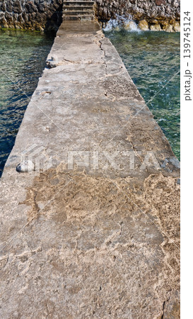Weathered concrete pier leading to stone stairs by the sea 139745124
