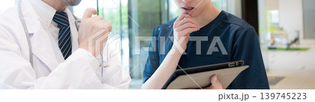 タブレットを見ながら指導や申し送りする医師と新人ドクターや看護師医療現場のDX 考える 顔無バナー 139745223