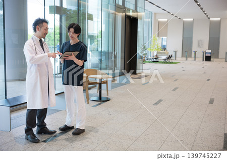 タブレットを見ながら指導や申し送りする医師と新人ドクターや看護師チーム連携イメージ全身 タブレットを見ながら指導や申し送りする医師と新人ドクターや看護師チーム連携イメージ全身 139745227