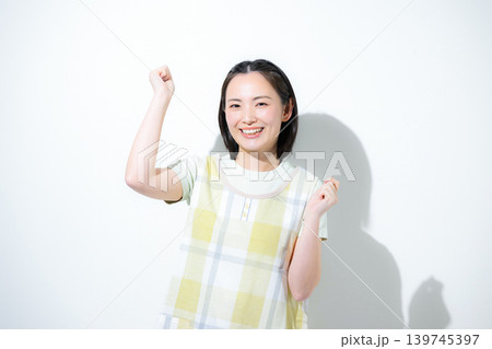 白背景で保育士や介護士、お母さんなど、働く女性の笑顔とガッツポーズ応援カメラ目線の笑顔　転職や求人 139745397