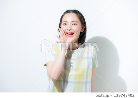 白背景で保育士や介護士、主婦として働く、応援や口コミなどのカメラ目線で笑顔のエプロンを付けた女性 139745402