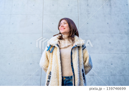 コンクリート壁の前で微笑む若い女性 139746699