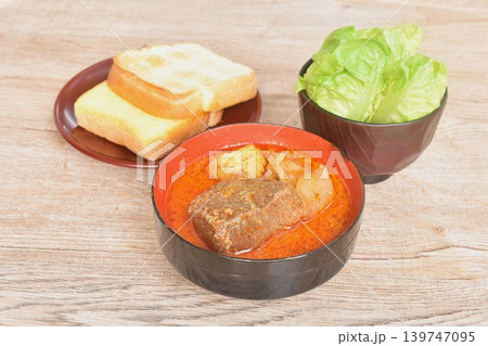 beef curry or Mussamun Indian food with slice potato and tomato on bowl eat couple fresh cos lettuce salad and grilled butter toast bread beef curry or Mussamun Indian food with slice potato and tomato on bowl eat couple fresh cos lettuce salad and grilled butter toast bread 139747095