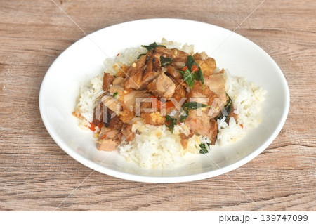 spicy fried slice crispy pork with chili and basil topping on plain rice in plate 139747099