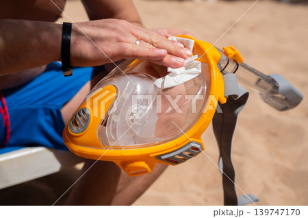 Caucasian man cleaning full face snorkeling mask on beach at Red Sea resort in Sharm El Sheikh Egypt. Travel and diving lifestyle 139747170