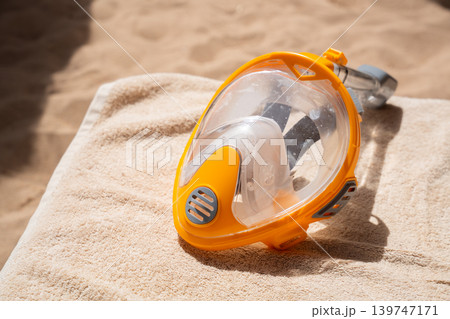 Orange full face snorkeling mask on beach lounge chair at Red Sea resort in Sharm El Sheikh Egypt. Travel and diving lifestyle Orange full face snorkeling mask on beach lounge chair at Red Sea resort in Sharm El Sheikh Egypt. Travel and diving lifestyle 139747171
